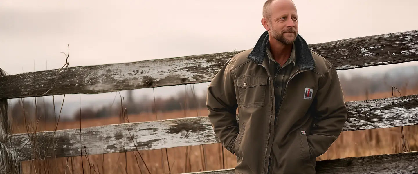 Man wearing International Harvester jacket standing next to a wooden fence